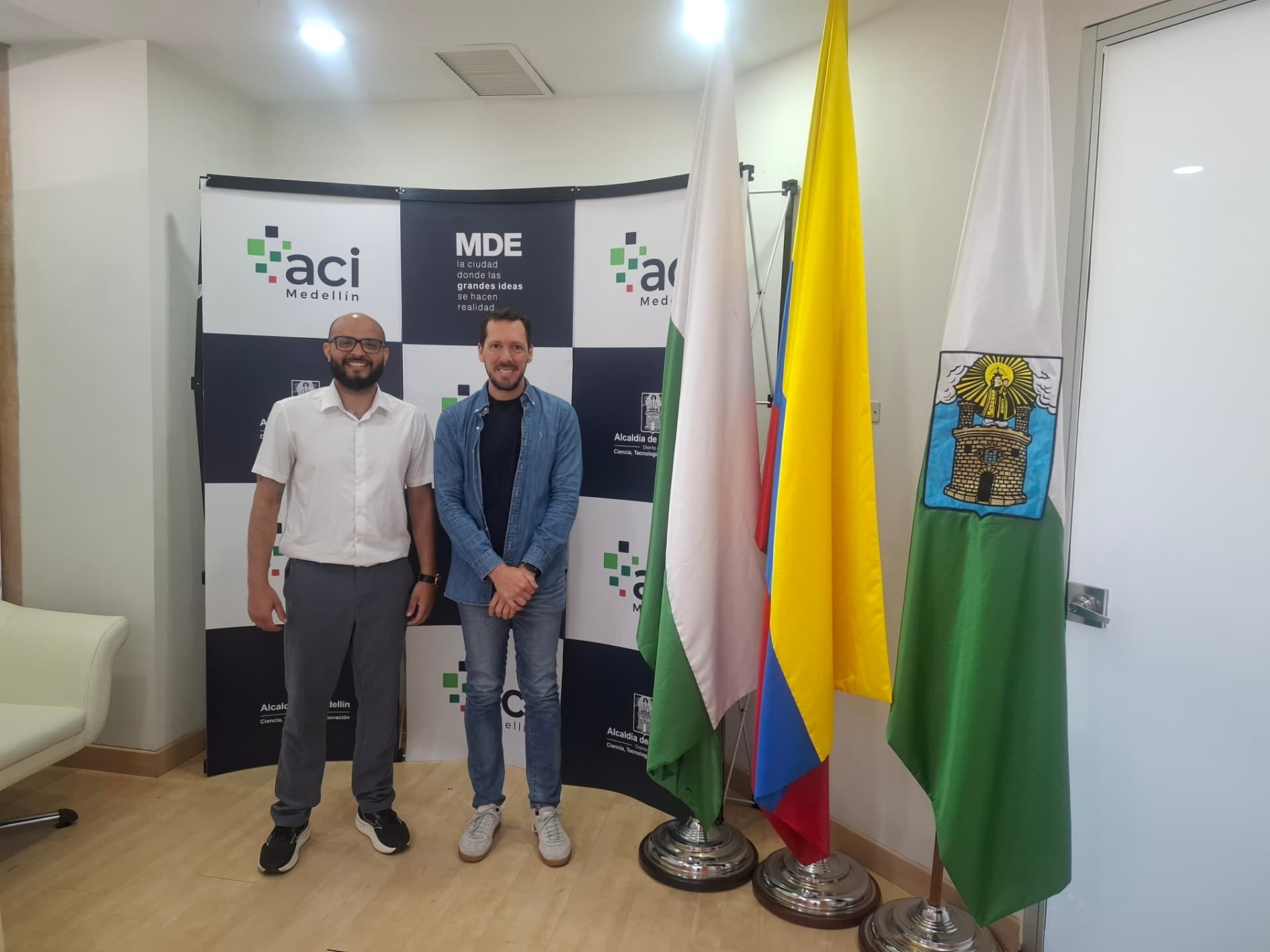 Tiago em encontro na Colômbia, ao lado de bandeiras e painel institucional