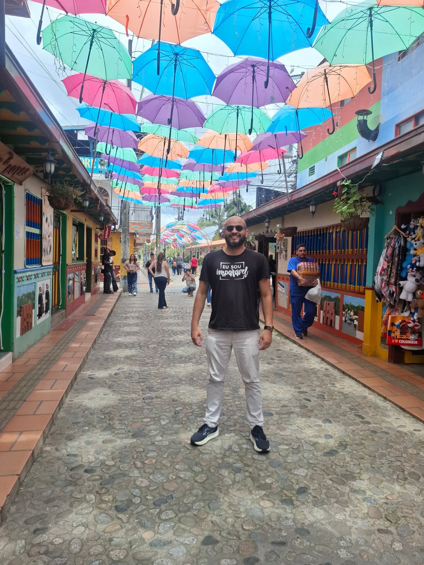 Tiago em uma rua decorada com guarda-chuvas coloridos na Colômbia
