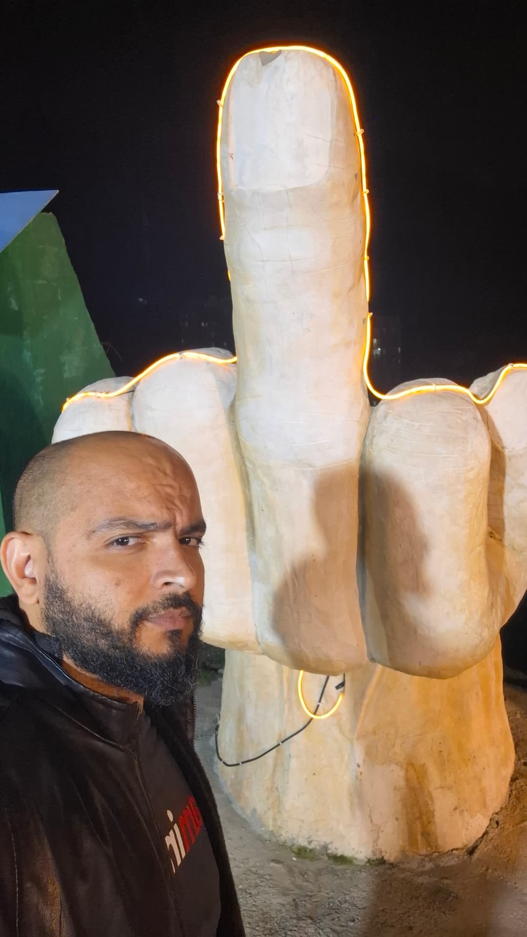 Tiago ao lado de uma escultura de mão iluminada durante a viagem
